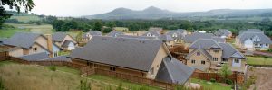 A neighborhood scene featuring houses with slate tile roofs and a majestic mountain in the background.