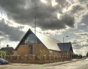 A church featuring a prominent cross atop its slate roof, showcasing the distinctive Del Carmen slate design.
