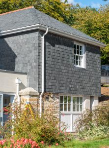 A house featuring a slate grey roof and a white door, showcasing modern architectural design.