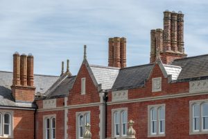 Close-up of red brick chimneys and slate gables on a historic building.