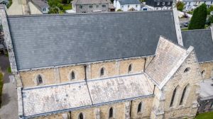 Aerial view of St Paul's Church showing the large dark slate main roof and the lighter stone-tiled roof of the lower side chapel,