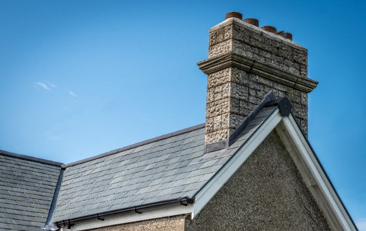 A cottage gable end showing the Riverstone slate roof meeting a stone chimney stack