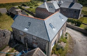 An elevated view of a traditional stone barn at Berry Farm featuring a newly installed Riverstone slate roof with terracotta ridge tiles and integrated skylights.