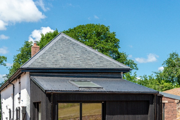 Close-up of the hipped roof at Bakers Cottage featuring SSQ Riverstone Ultra Natural Slate above a black timber extension.
