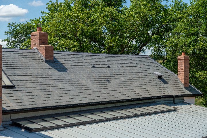 Main roof slope of Bakers Cottage showcasing the authentic heritage finish of Riverstone Ultra Natural Slate and traditional brick chimneys.
