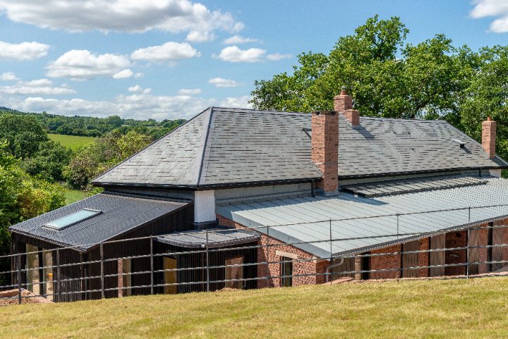 Exterior view of the property highlighting the newly installed natural slate roof alongside the brick and black timber elevations.
